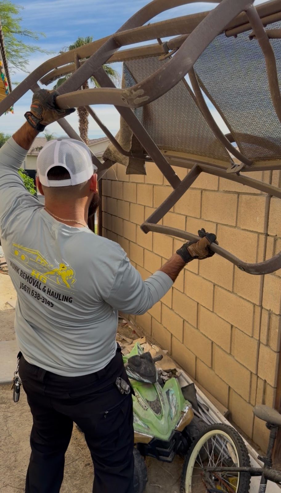 HG crew member removing old patio furniture from a side yard