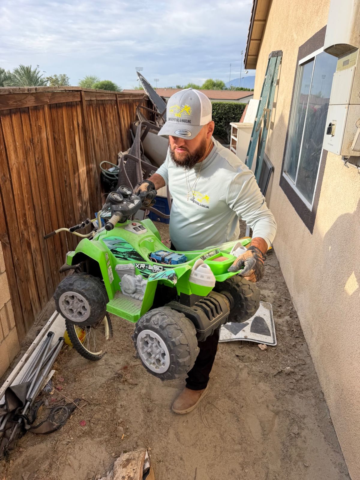HG crew member carrying a child's ride-on ATV out of a side yard